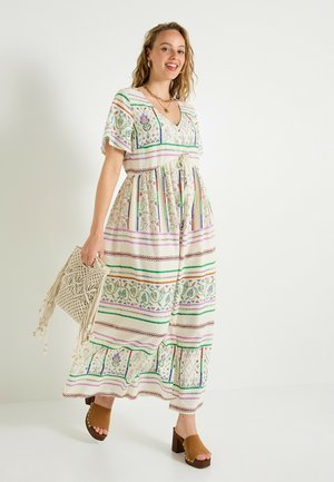 Robe maxi en tissu léger avec des motifs rayés verts, violets et rouges. Dotée d'un col en V, d'une taille à nouer et de manches courtes ; associée à des sabots marron.
