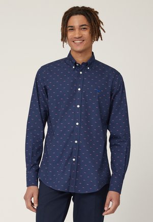 Camicia blu navy con bottoni, caratterizzata da un motivo ripetuto di piccoli cani rosa, maniche lunghe e colletto classico. Tessuto liscio e vestibilità standard.
