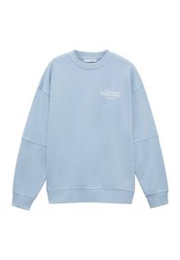 Felpa azzurra con collo rotondo, spalle abbassate e polsini a coste. Presenta un discreto marchio "Lacoste Badminton" bianco sul petto.