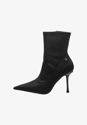 Botín de tela negra hasta el tobillo con punta afilada, tacón de aguja y cierre de cremallera. Textura suave con detalle de costura visible en el puño.