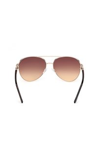 Gafas de sol aviador con lentes en gradiente marrón, marco de metal dorado y delgadas varillas de acetato negro. Incluye almohadillas nasales de silicona transparentes.