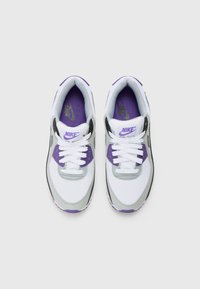 Nike tenisice s gornjim dijelom od bijele mrežice s ljubičastim i sivoj naglasima, crnim potplatom i bijelim vezicama. Logo prikazan na jeziku i umetak.