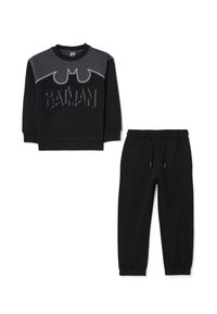 Felpa nera in cotone con logo di Batman, caratterizzata da pannelli grigi e scritte testurizzate; abbinata a pantaloni della tuta neri con polsini elasticizzati.