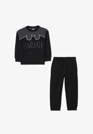 Felpa nera in cotone con logo di Batman, caratterizzata da pannelli grigi e scritte testurizzate; abbinata a pantaloni della tuta neri con polsini elasticizzati.