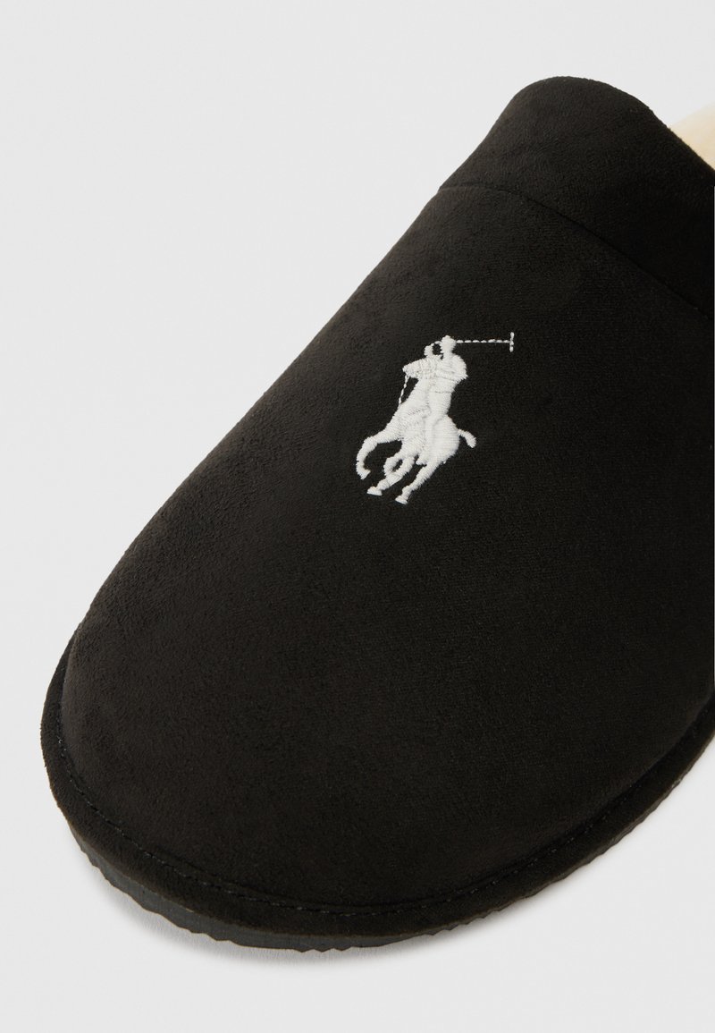 Schwarze Wildlederschlappen mit einem weißen, gestickten Polo-Spieler-Logo auf der Oberseite, mit einer abgerundeten Spitze und einem strukturierten Sohlenrand.
