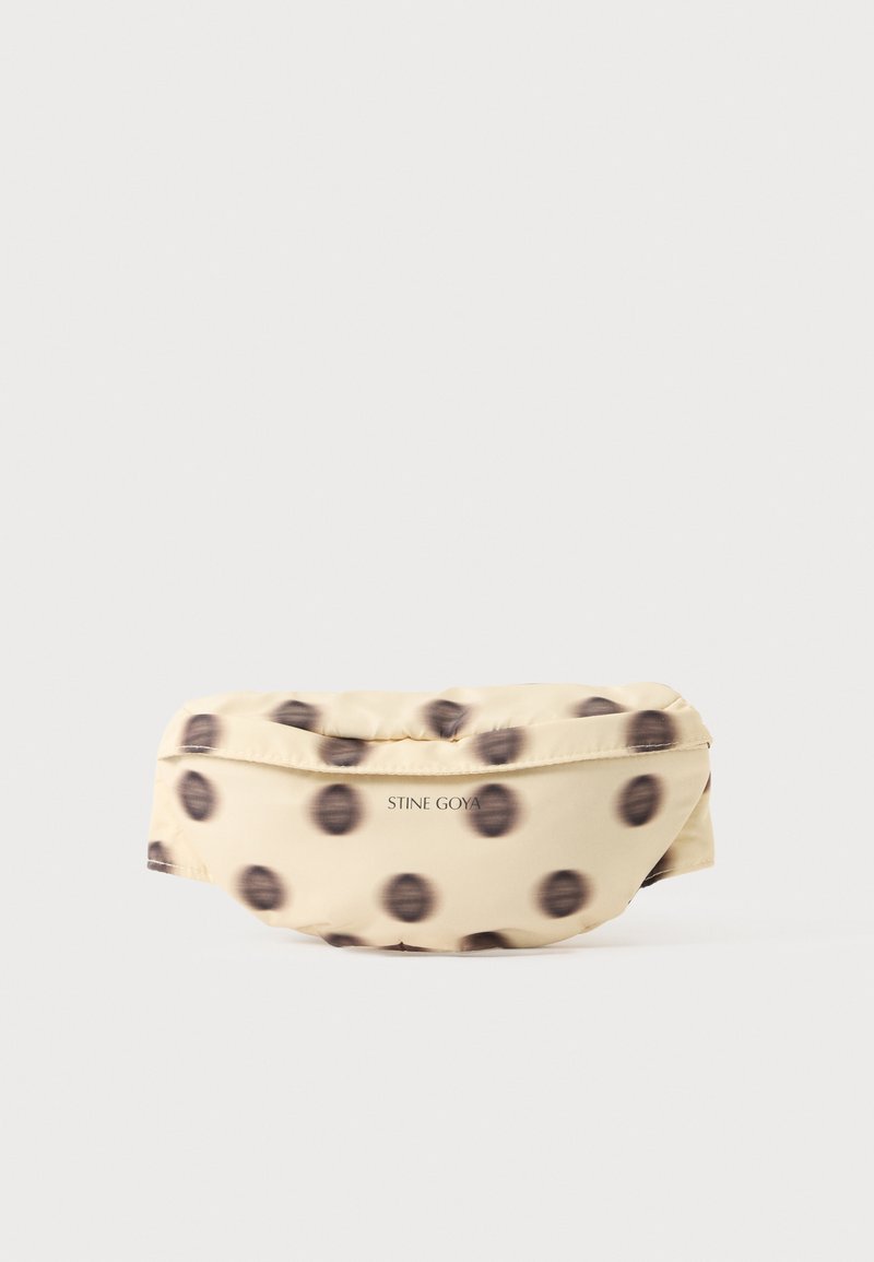 Banane en tissu beige avec des pois noirs flous et "STINE GOYA" imprimé en petites lettres noires à l’avant.