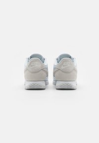 Nike apavi ar gaiši zilu sintētisku virsu, pelēku zamšādas akcentiem, mīkstu apkakli un teksturētu pelēku gumijas zoli.