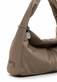 Zachte taupekleurige leren schoudertas met een zilveren ketting en een ronde hanger, voorzien van zichtbare stiksels en een merkembleem aan de zijkant.