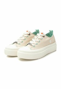 Zapatillas de lona beige con una suela de plataforma blanca texturizada, detalles en verde menta y herrajes plateados. Cuentan con cordones y un logo decorativo de flor.