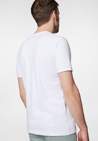 Biała bawełniana koszulka z krótkimi rękawami i okrągłym dekoltem, o gładkiej fakturze i delikatnym logo z tyłu.