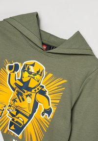 Olivgrön huvtröja med en stor gul grafisk bild av en LEGO-riddare. Har en ficka fram och dragsko i huvan. Mjuk textur.