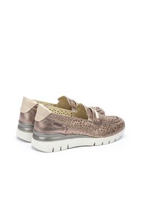 Zapatos de deslizamiento de bronce metálico con diseño perforado, punta redondeada, acentos en crema y suela blanca acolchada.