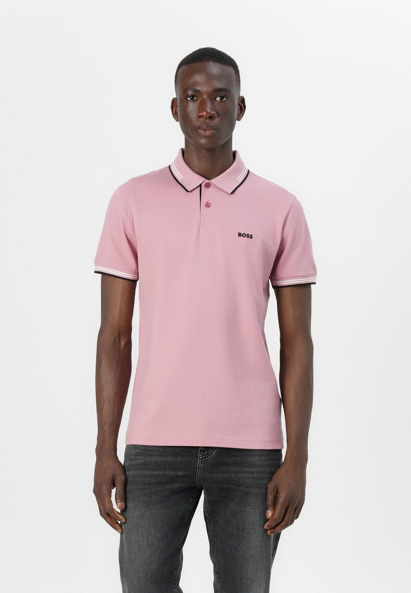 Ljusrosa polo t-shirt med svart krage och ärmtrimmar, med en liten svart logotyp på vänster bröst. Slät bomullstyg.