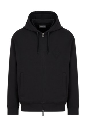 Hoodie zippé noir en tissu doux, avec une capuche à cordon, des poches frontales, des poignets côtelés, et un logo embossé subtil sur la poitrine.