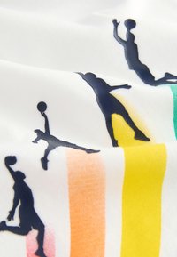 Fehér anyag, amelyen több kosárlabdajátékos sziluettje látható tengerészkék színben, színes, narancssárga, sárga és zöld csíkos díszítéssel.