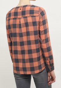 Långärmad rutiga skjorta i orange och marinblå med knäpp ärmar, ryggveck och rundad nederkant. Mjuk tyg med rutmönster.