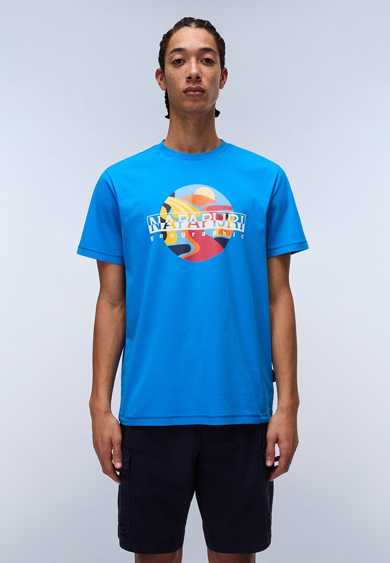 Modré bavlněné tričko s grafickým designem s kruhovými vzory v oranžové, žluté a červené barvě, a textem "Napapijri Geographic" uprostřed.