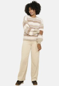 Svītrots džemperis ar bēšiem un gaiši rozā toņiem, ar mīkstu, teksturētu apdari. Apvienots ar gaišām kordfota biksēm un tumšām kurpēm.