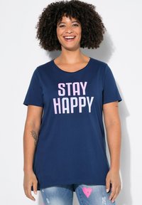 Námorně modré tričko s krátkým rukávem s nápisem "STAY HAPPY" vytištěným reflexními růžovými písmeny. Měkký materiál s volným střihem a kulatým výstřihem.