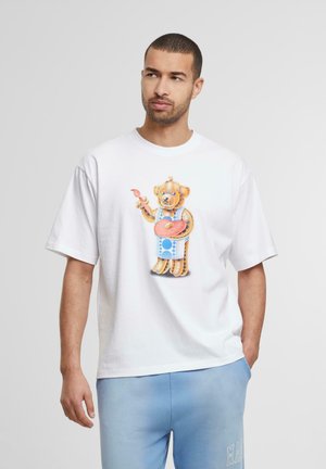 Witte katoen t-shirt met een kleurrijke geïllustreerde beer die een rood bord vasthoudt, met blauwe accenten op de kleding van de beer. Korte mouwen.
