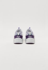 White athletic shoes with purple accents and a textured sole, featuring a prominent logo on the heel and a pull tab for easy wear.