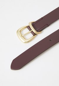 Burgundy leather belt with a gold rectangular buckle, featuring stitched accents and a tapered end. Includes a single hole for adjustment.