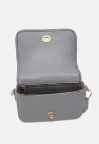 Borsa a tracolla in pelle grigia aperta per mostrare la tasca interna con zip e hardware dorato, inclusi clip e chiusura magnetica.