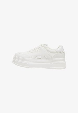 Sneaker bianca low-top con suola spessa, chiusura frontale con lacci e tomaia in tessuto strutturato, vista laterale su sfondo bianco.