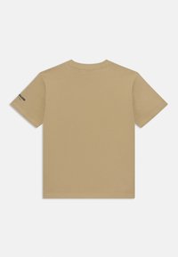 T-shirt à manches courtes en beige clair, fabriqué en coton doux avec un col rond ; présente un petit détail imprimé sur la manche gauche.