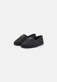 Sorte espadrilles uden hæl med struktureret stof, flettet jutesål og en sølvfarvet logoaccents foran. Glat overflade og lav profil design.