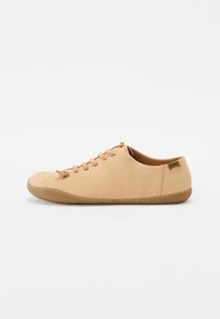 Beige minimalista cipő sima bőrből, lekerekített orral, hat fűzőlyukkal és rugalmas gumi talppal, amelyen varrási részletek találhatóak.
