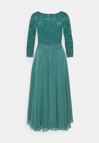 Robe longue à manches longues couleur sarcelle avec corsage en dentelle et jupe en chiffon transparent et fluide, fermeture éclair au dos.