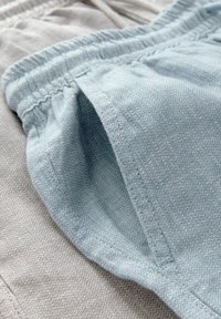 Lichtblauwe en lichtgrijze stof die met elkaar verweven is, met elastische taillebanden, textuurweefsels en kleine zijzakken in een casual stijl.