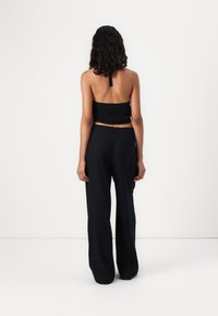 Zwart cropped brei-top met een vierkante halslijn, gecombineerd met hoge taille, brede zwarte broek. Minimalistisch ontwerp zonder zichtbare patronen.