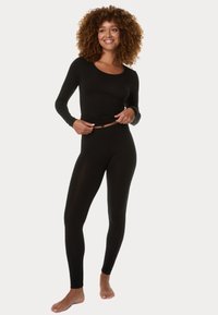 Černý top s dlouhými rukávy a odpovídající legíny vyrobené z měkkého, elastického materiálu; přiléhavý střih s kulatým výstřihem a bez viditelných vzorů.
