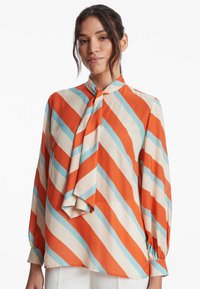 Seidenbluse mit langen Ärmeln, die diagonale orange, hellblaue und cremefarbene Streifen aufweist, sowie ein Schleifenkragen-Detail.