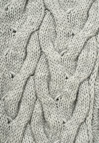 Tissu tricoté gris clair avec un motif texturé de câble entrelacé. La laine épaisse donne une apparence chaleureuse et confortable.