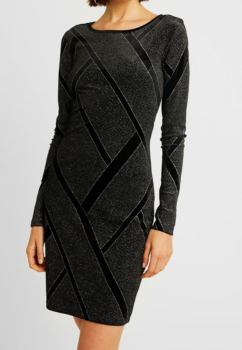 Schwarz langärmliges Kleid mit geometrischem Muster, strukturierten Oberflächen und glänzenden Akzenten. Figurbetonte Silhouette, Rundhalsausschnitt.