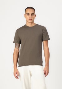 Kaki Kurzarm-T-Shirt aus Baumwolle, mit einem Rundhalsausschnitt und einem lockeren Schnitt. Mit glatter, einfarbiger Textur gestaltet.