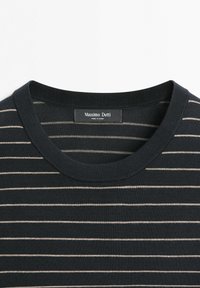 Zwarte trui met ronde hals en dunne witte horizontale strepen, met een "Massimo Dutti" label dat in de kraag is genaaid.