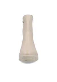 Botín beige hasta el tobillo hecho de cuero suave con punta redonda, cremallera lateral y suela de goma texturizada. La altura es a media pantorrilla. Diseño minimalista.