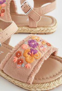 Pfirsichfarbene Leinensandalen mit ausgefransten Kanten und buntem floralen Stickereien. Jutebelegte Sohle, verstellbares Schnallendetail und gepolsterte Innensohle.