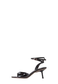 Sandal in vernice nera con punta aperta e sottile cinturino alla caviglia. Presenta un tacco a stiletto basso e un design minimalista per un aspetto elegante.