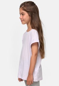 T-shirt di cotone viola chiaro con maniche corte arrotolate, scollo rotondo e vestibilità ampia, mostrata su un bambino di lato.