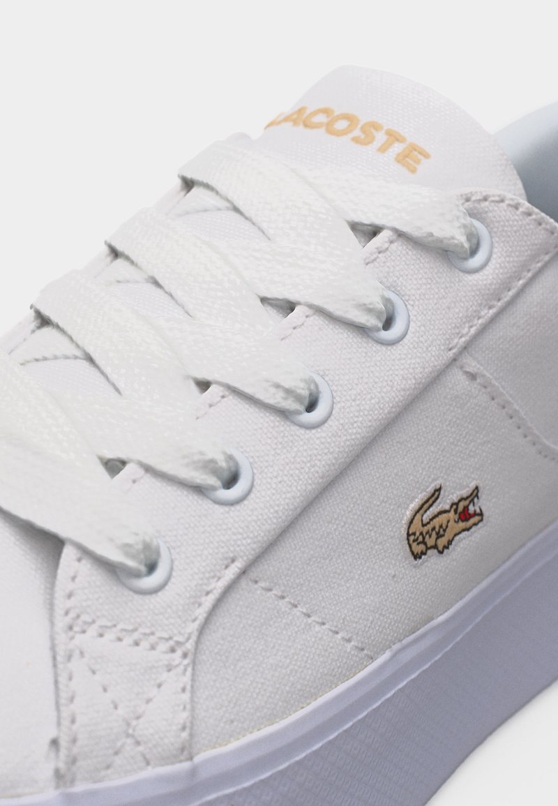 Sneaker bianca Lacoste con lacci bianchi, logo coccodrillo beige sul lato e scritta "LACOSTE" beige sulla linguetta.