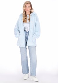 Jasnoniebieska, puszysta kurtka z kapturem, luźnym krojem i przednimi kieszeniami, w połączeniu z pasiastą koszulą i jasnoniebieskimi jeansami. Białe trampki.