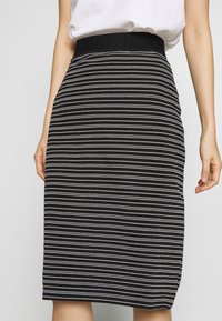 Schwarz-weißer gestreifter Rock mit figurnahem Design, strukturiertem Stoff und breitem schwarzen Bund. Das Muster zeigt horizontale Linien und Punkte.