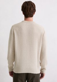 Sweter w kolorze kremowym, miękka tekstura, okrągły dekolt, ściągacze na rękawach i u dołu. Prosty krój bez widocznych wzorów czy elementów metalowych.