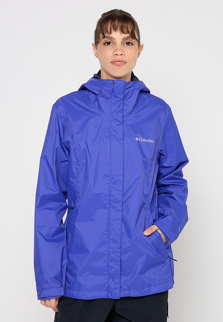 Veste Columbia légère, imperméable, de couleur violette, avec capuche, fermeture éclair à l'avant, cordon de serrage réglable et poches latérales. Texture lisse.