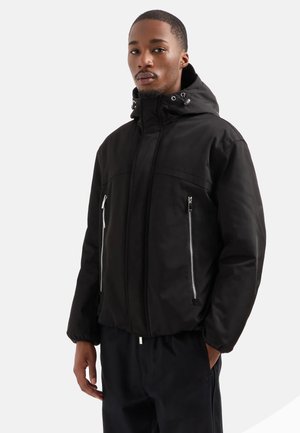 Giacca nera con cappuccio realizzata in materiale resistente all'acqua, dotata di tasche frontali con cerniera, cappuccio regolabile con cordino e vestibilità rilassata.